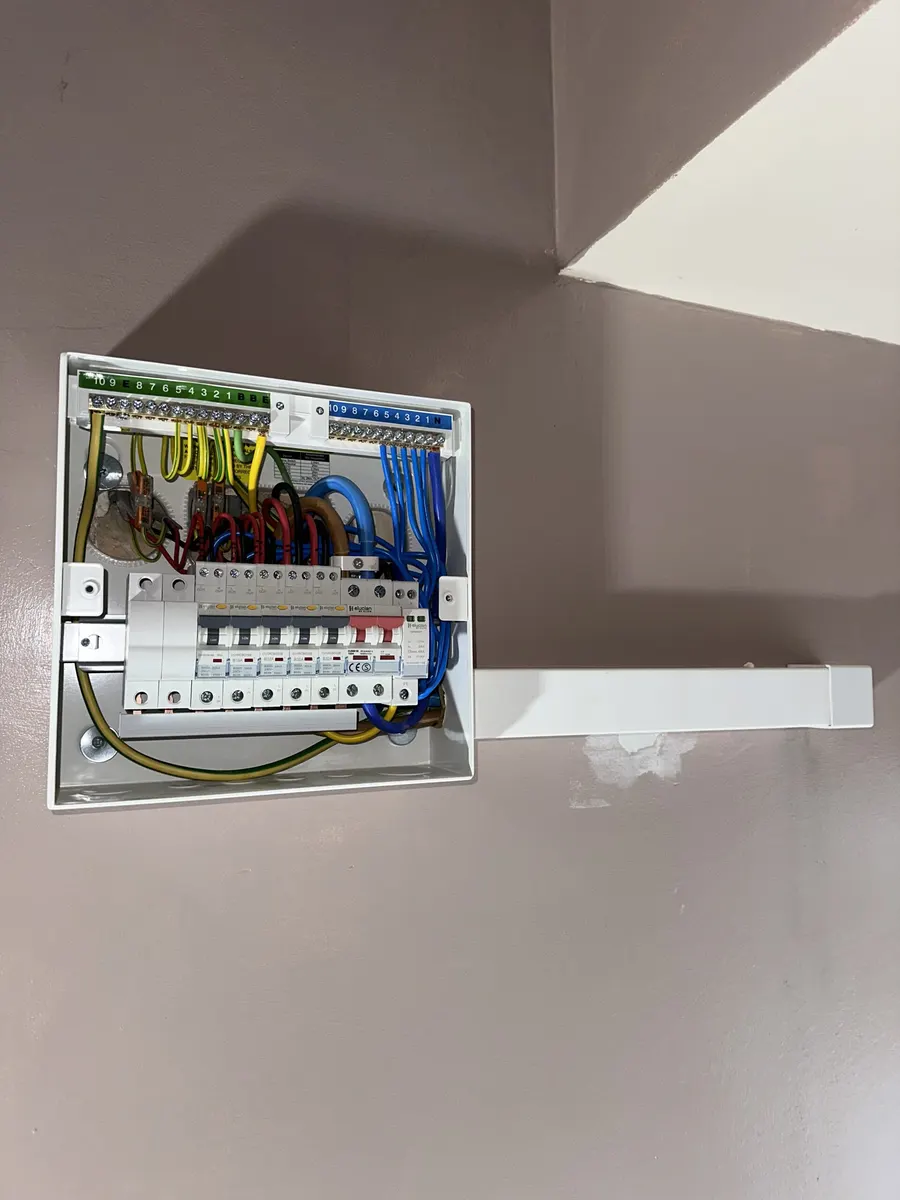 Consumer unit with its cover removed, mounted on a wall beside a staircase