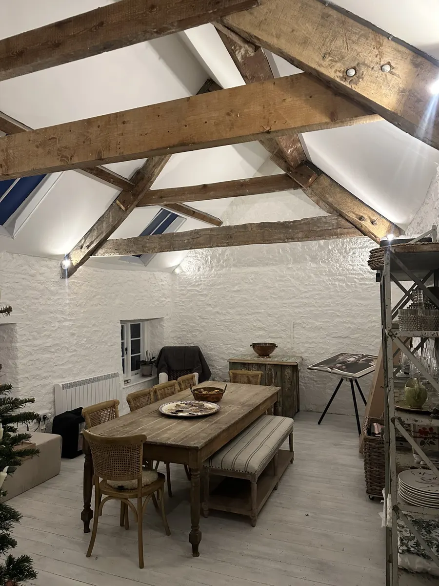 Dining room with exposed roof timbers, white stone walls and pendant lighting