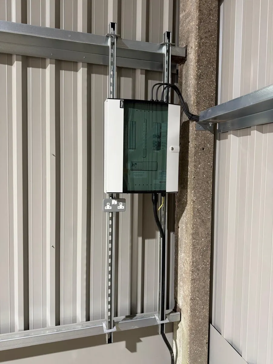 Electrical distribution enclosure with a tinted cover, mounted on metal strut beside a concrete column inside a metal-clad building