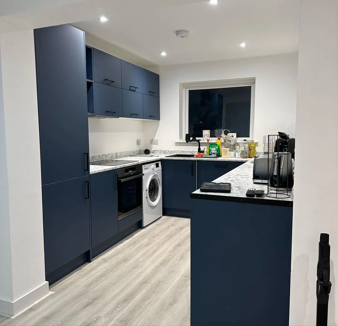 Newly fitted kitchen with navy cabinets, integrated appliances and downlights