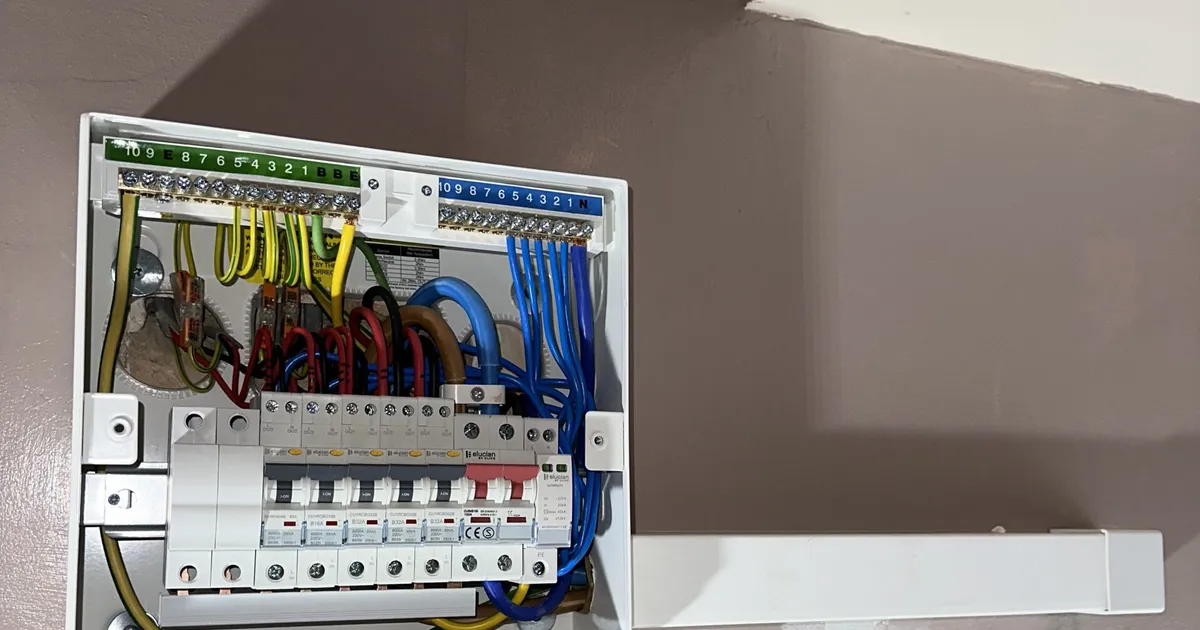 Consumer unit with its cover removed, mounted on a wall beside a staircase