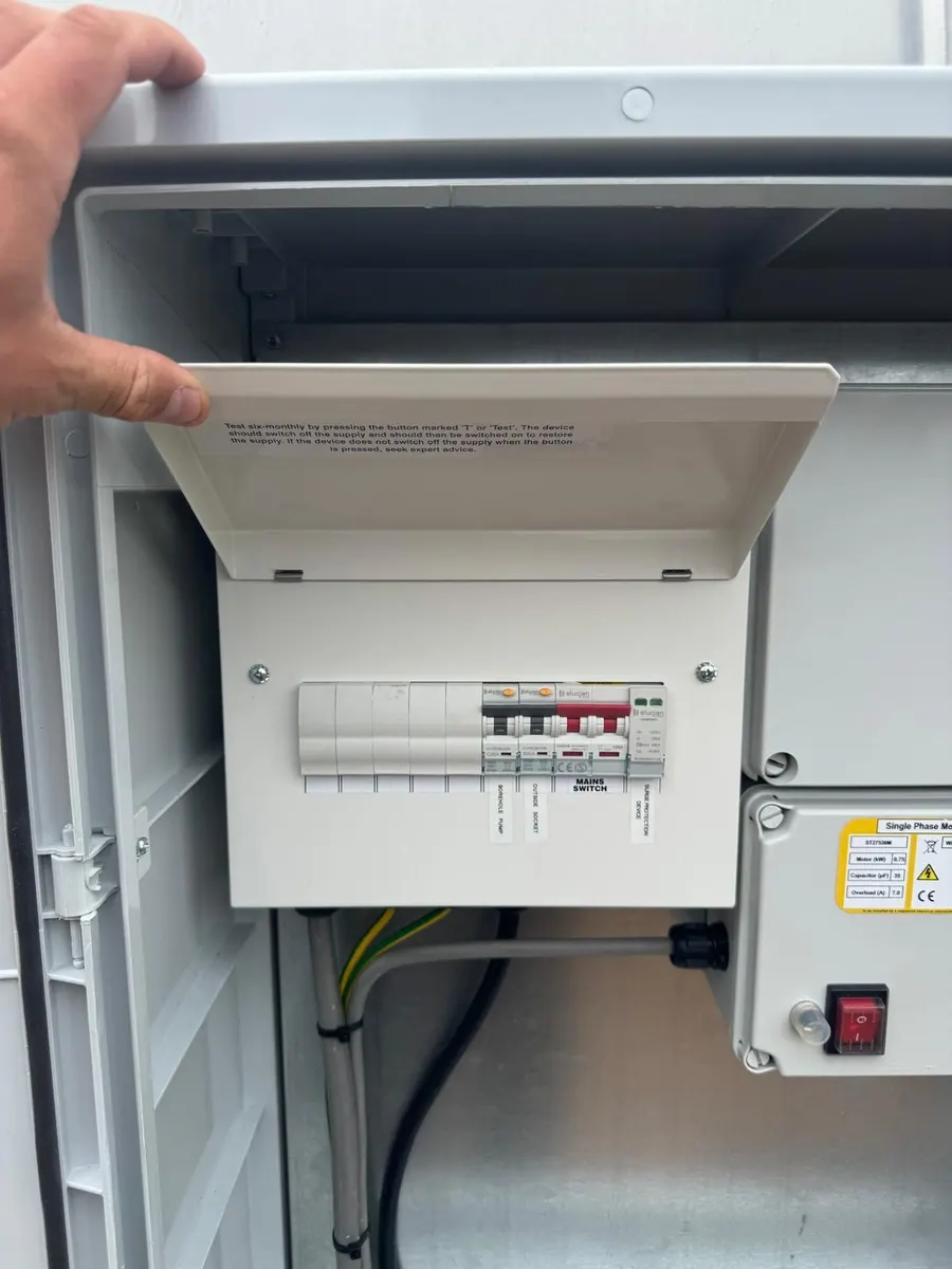 Small consumer unit inside a grey enclosure, with circuits labelled borehole pump and outside socket beside a motor starter