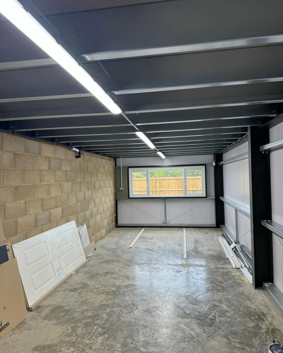 Unfurnished unit with exposed steel ceiling beams, illuminated linear battens, block wall and window at the far end