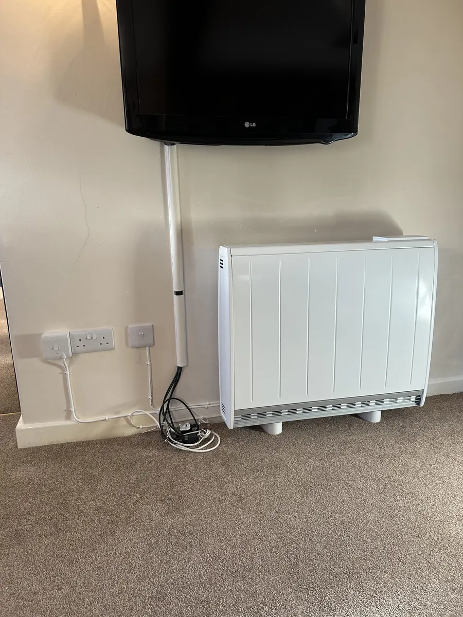 Electric storage heater beside sockets and a television connection