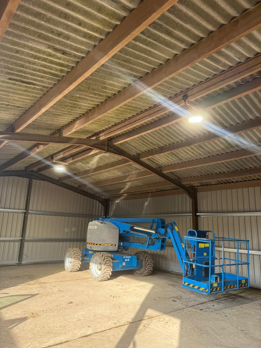 Farm barn with LED high-bay lights under a steel and timber roof, access platform parked inside
