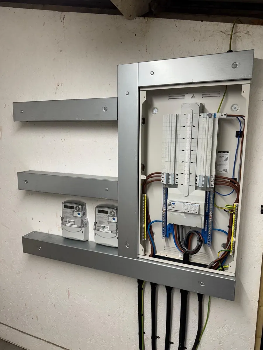 Hager board with cover off beside two meters labelled Barn 1 and Barn 2, cables dressed down from the trunking