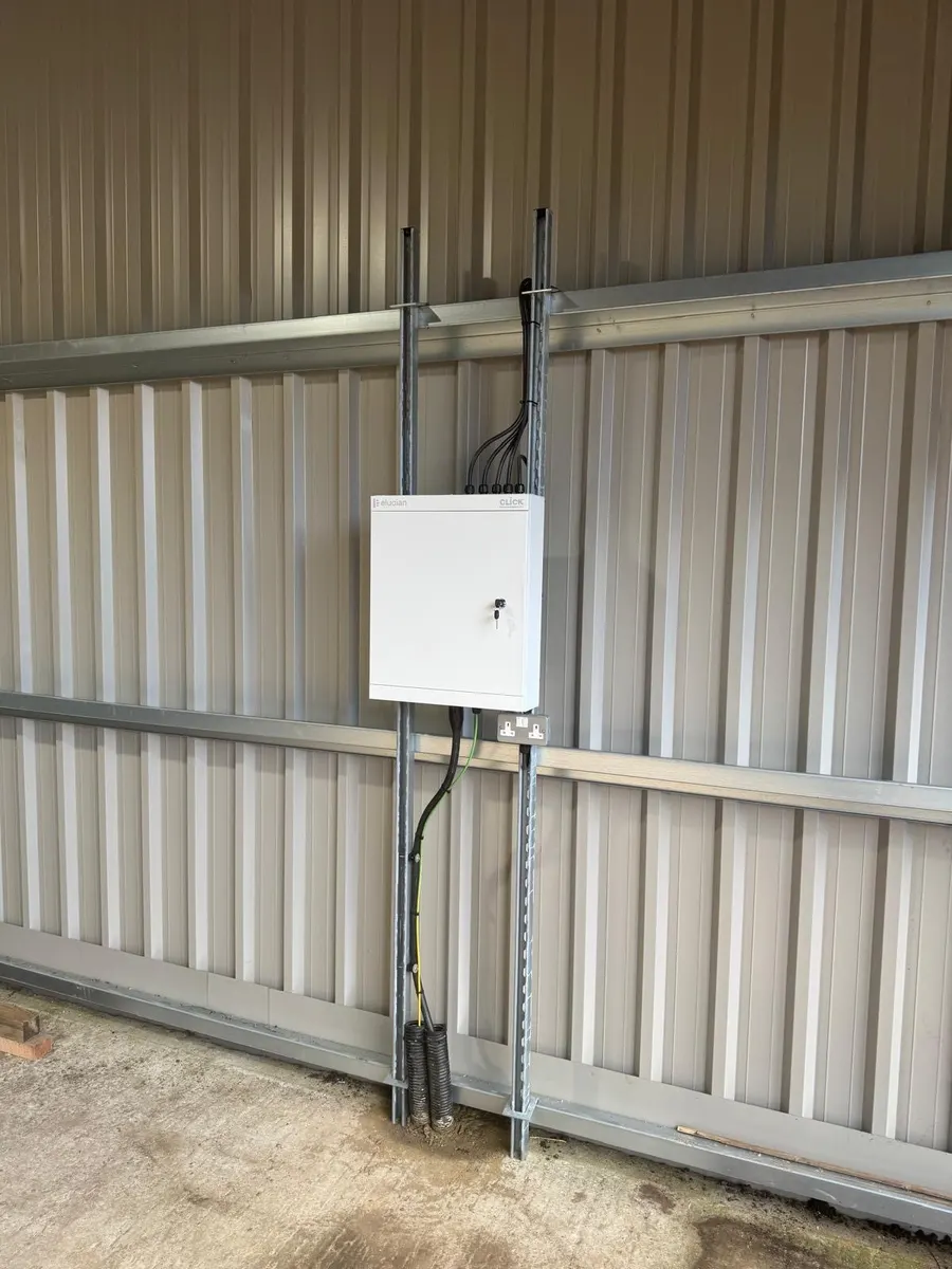 Locked white sub-board on strut channel against a steel wall, cables entering at the top and a double socket below