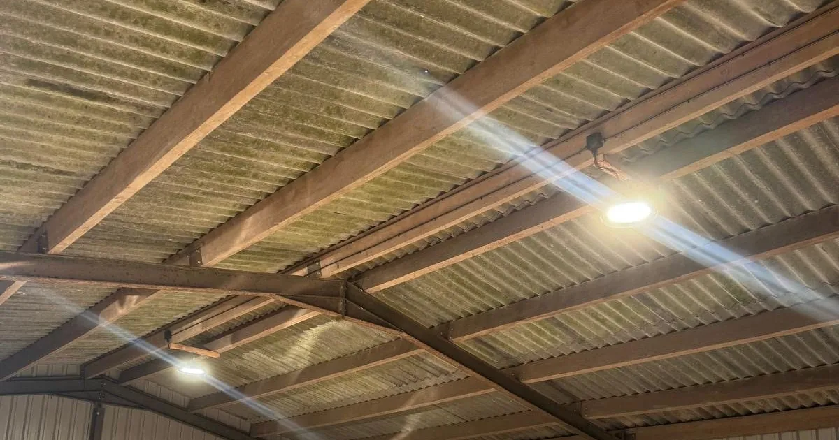 Farm barn with LED high-bay lights under a steel and timber roof, access platform parked inside